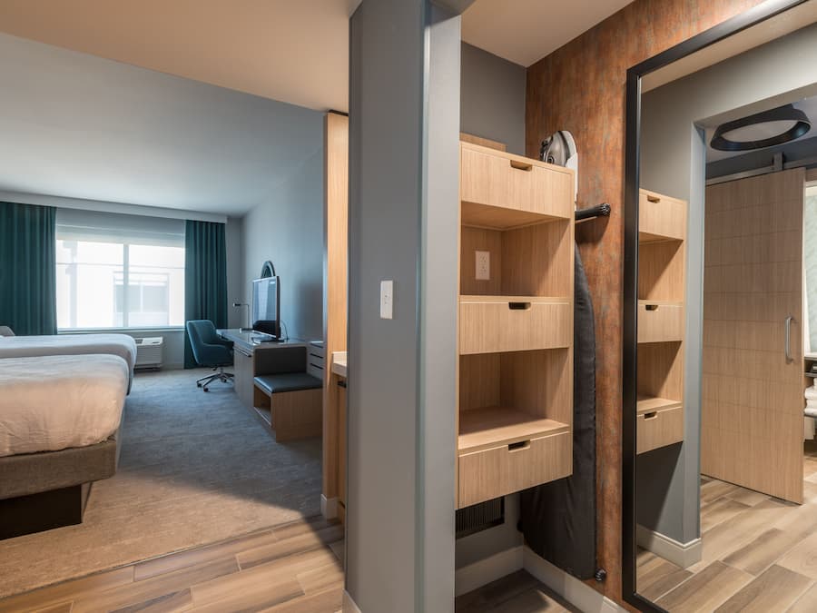 Una habitación de hotel moderna con cama, escritorio, silla y armario empotrado.
