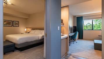 A modern hotel room with a bed, desk, and seating area.