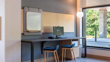 A modern office space with a desk, computer, and two blue chairs.