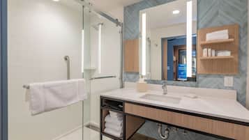 A modern bathroom with a glass shower enclosure, a vanity with a mirror, and a towel rack.
