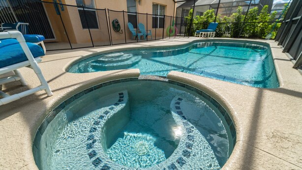 Una piscina con due vasche idromassaggio, circondata da lettini e da una recinzione.