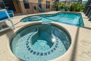 Ein Swimmingpool mit zwei Whirlpools, umgeben von Liegestühlen und einem Zaun.