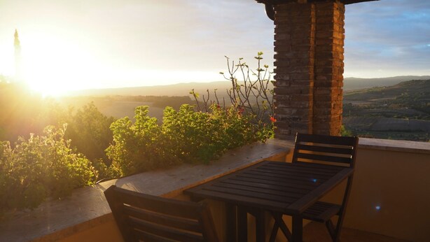 A terrace with a table and chairs, overlooking a scenic landscape with a distant tower. - Only ten minutes walk to the golf course and still very quiet (Saturnia)