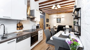 A modern kitchen with white cabinets, a built-in oven, and a dining area with a table and chairs.