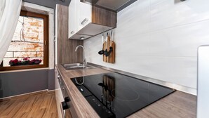 A modern kitchen with a built-in stove, wooden cabinets, and a window with flowers.