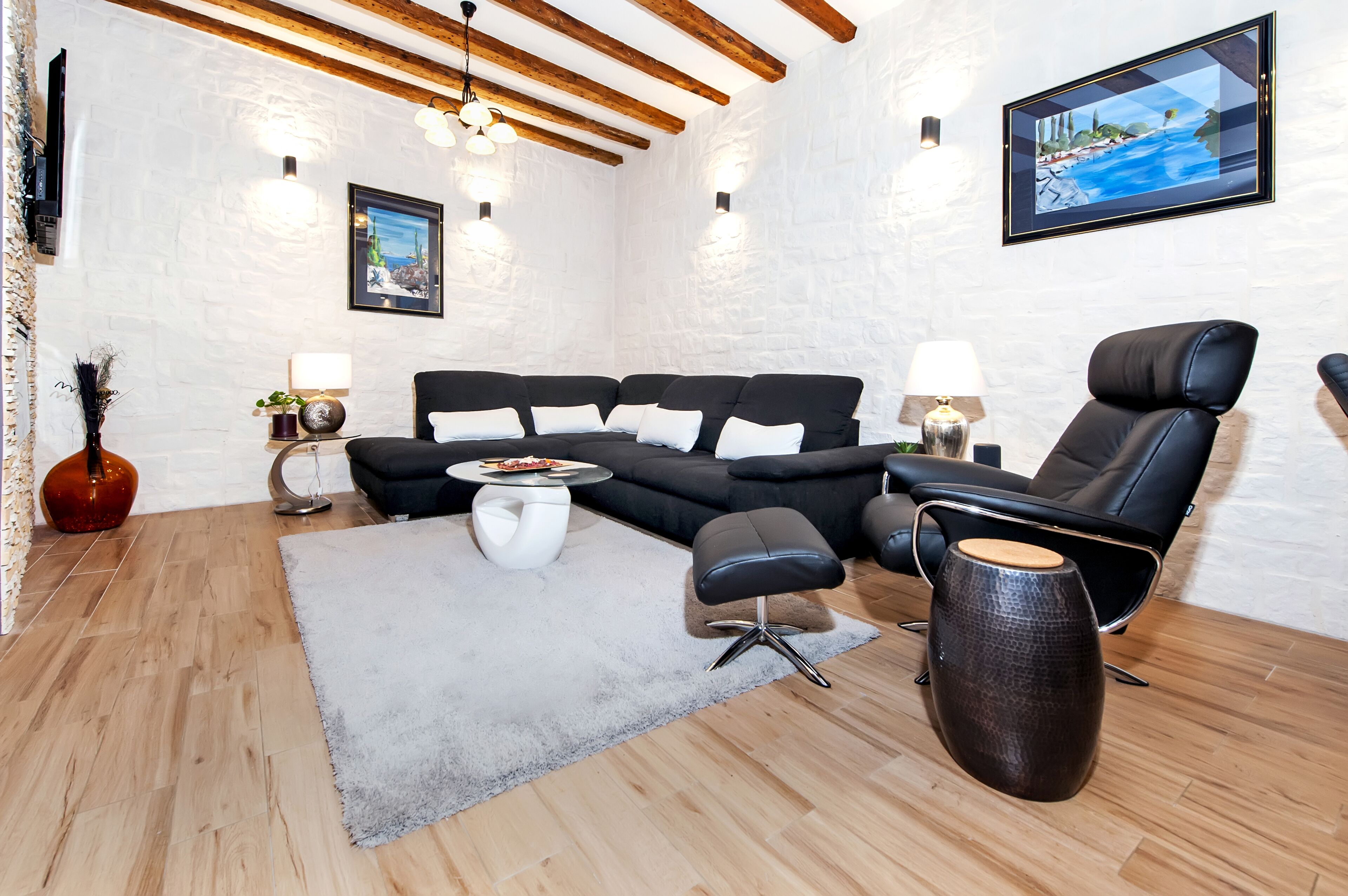 Una sala de estar moderna con un sofá seccional, un sillón de cuero negro, una mesa de centro y un jarrón grande.