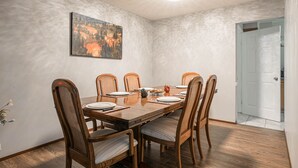 A dining room with a wooden table set for six, surrounded by six chairs. - Entire house, 6 BR/3BA, All Queen Beds, Central location  (Calgary)