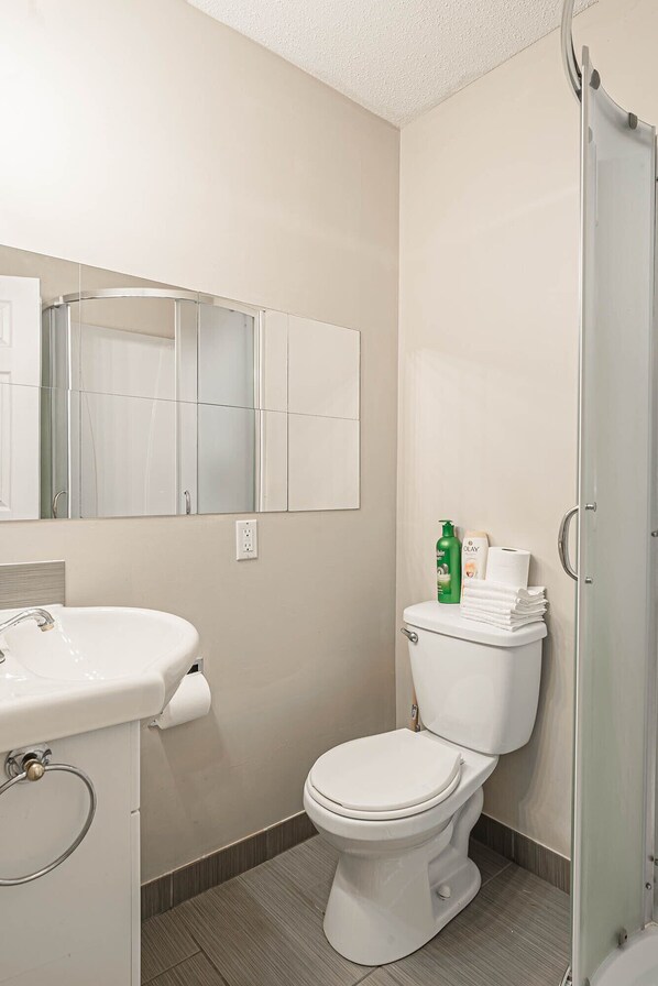 Une salle de bain moderne avec un lavabo blanc, des toilettes et une douche à parois de verre.