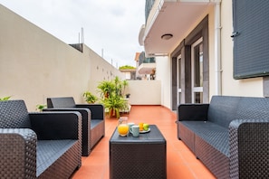 Un área de estar al aire libre con mobiliario de mimbre y una mesa con bebidas.