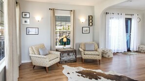 A living room with two patterned armchairs, a wooden coffee table, and a cowhide rug.