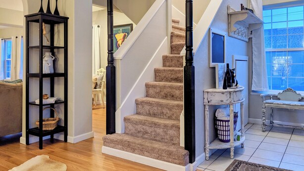 A staircase with carpeted steps, a black column, and a white wall.