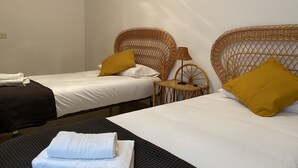 A hotel room with two single beds, each with a white sheet and a mustard-colored pillow. There is a small table with a lamp between the beds, and a folded white towel on the floor. - Huge Balcony over Las Canteras By CanariasGetaway (Las Palmas de Gran Canaria)