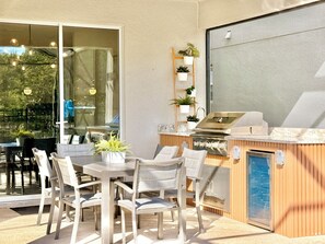 An outdoor patio with a grill, seating area, and potted plants.