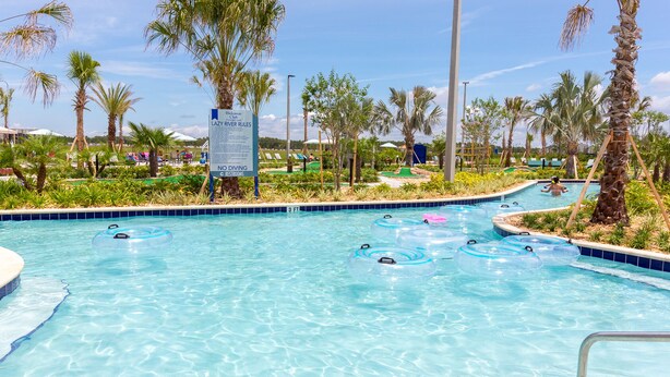 Un área de piscina con agua cristalina, sillas de descanso y palmeras.