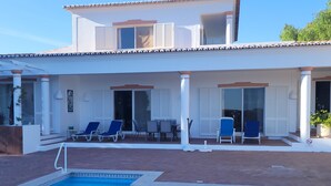 Ein zweistöckiges Gebäude mit Pool, Sitzgelegenheiten im Freien und einer Terrassenfläche.