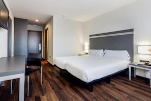 Una habitación de hotel con una cama grande, un escritorio y una silla.