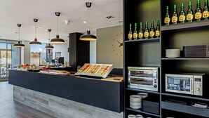 A modern breakfast bar with a variety of food options, a coffee machine, and a wine cooler stocked with bottles. - B&B Hotel Oviedo (Siero)