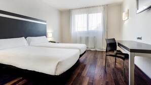 A hotel room with two beds, a desk, and a chair. - B&B Hotel Oviedo (Siero)