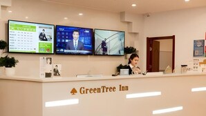 En receptionsdisk på GreenTree Inn med tre skærme, der viser forskelligt indhold.