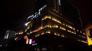Et hotel med flere etager, oplyst skiltning og moderne arkitektur.