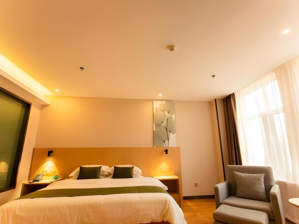 A hotel room with a bed, bedside tables, a chair, and a large window.