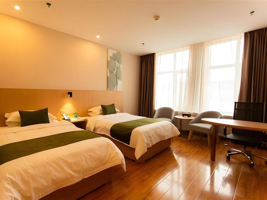A hotel room with two beds, a desk, a chair, and a TV.