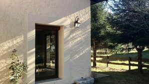 A building with a white exterior, a wooden door, and a small window. There is a metal gutter running along the roof edge, and a wooden fence is visible in the background. - ANCELLE Chalet-style house 160 m2 at the foot of the slopes (Ancelle)