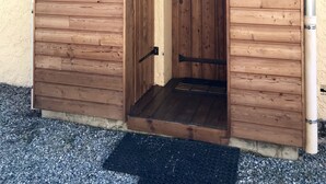 A wooden shed with a door and a small porch area. - ANCELLE Chalet-style house 160 m2 at the foot of the slopes (Ancelle)