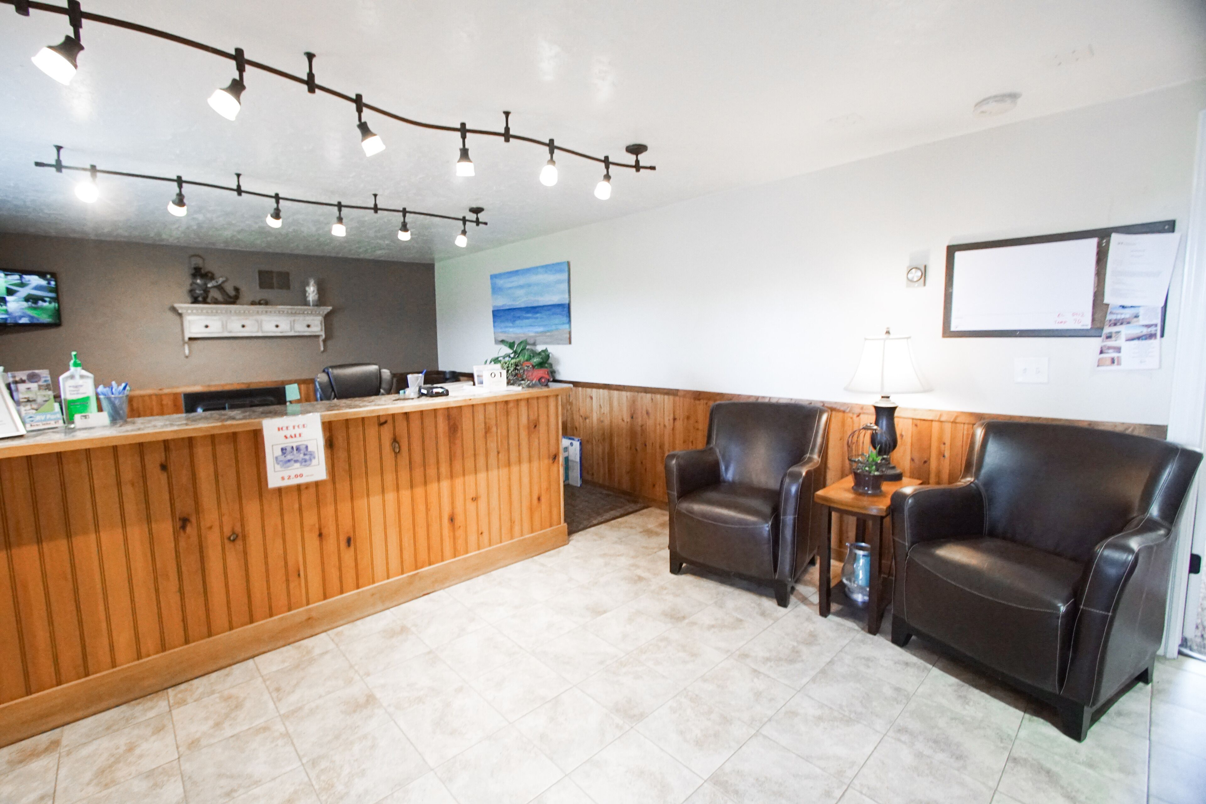 A reception area with a wooden counter, leather chairs, and a wall-mounted TV.