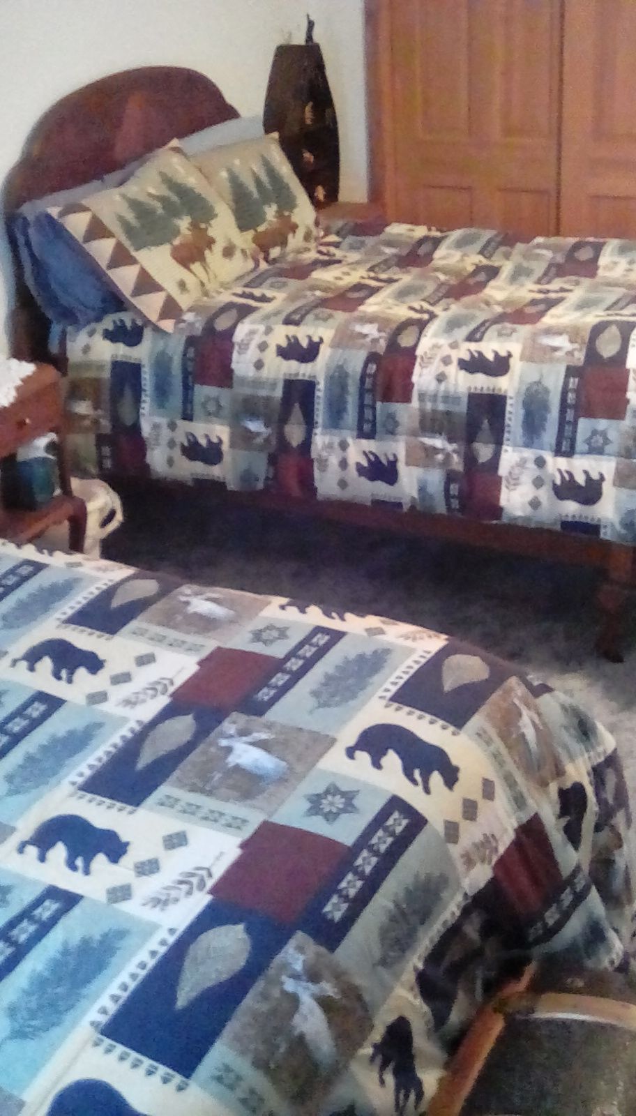 Een slaapkamer met twee bedden, elk met een quilt met een patroon.