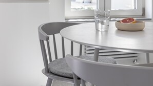 A dining area with a round table, two chairs, a bowl with a fruit, and a glass of water.