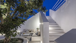 A modern interior with a staircase, seating area, and a potted plant.