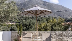 A pool area with a tiled floor, a chair, a table, and a potted plant.