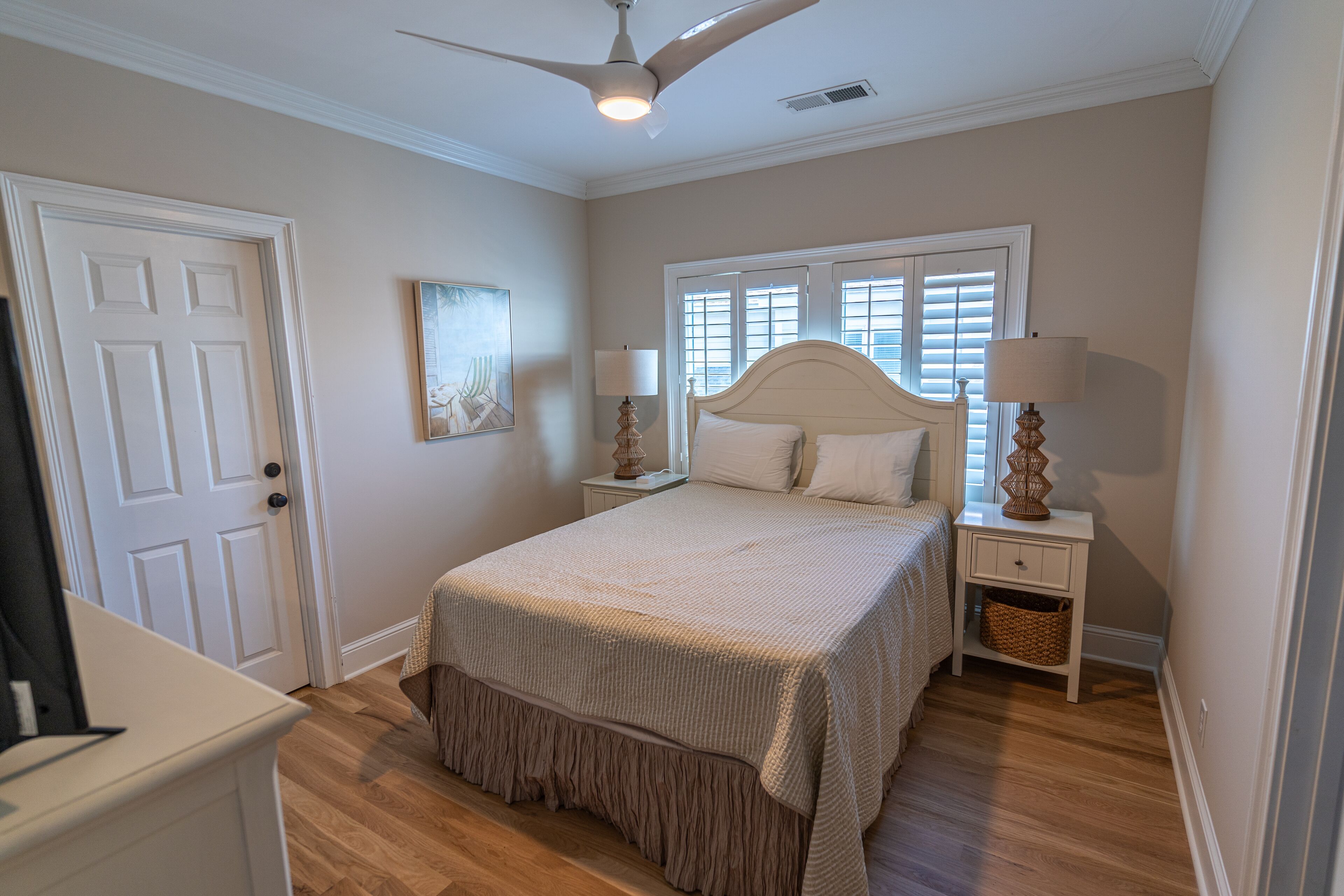A bedroom with a bed, nightstands, a ceiling fan, and a window with blinds.
