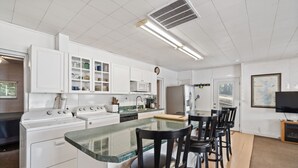 Eine moderne Küche mit weißen Schränken, einer zentralen Kochinsel mit Barhocker, einer Mikrowelle und einem Kühlschrank.