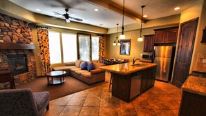 A spacious living area with a stone fireplace, a sofa, and a dining table. - Canyon Villas at Coral Ridge (Washington)