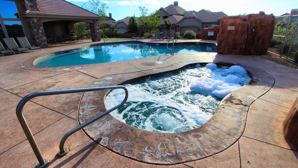 A swimming pool with a hot tub, surrounded by stone pillars and a stone deck. - Canyon Villas at Coral Ridge (Washington)