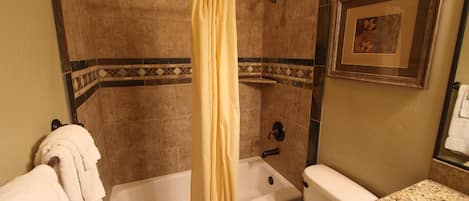 A bathroom with a bathtub, toilet, and shower curtain.