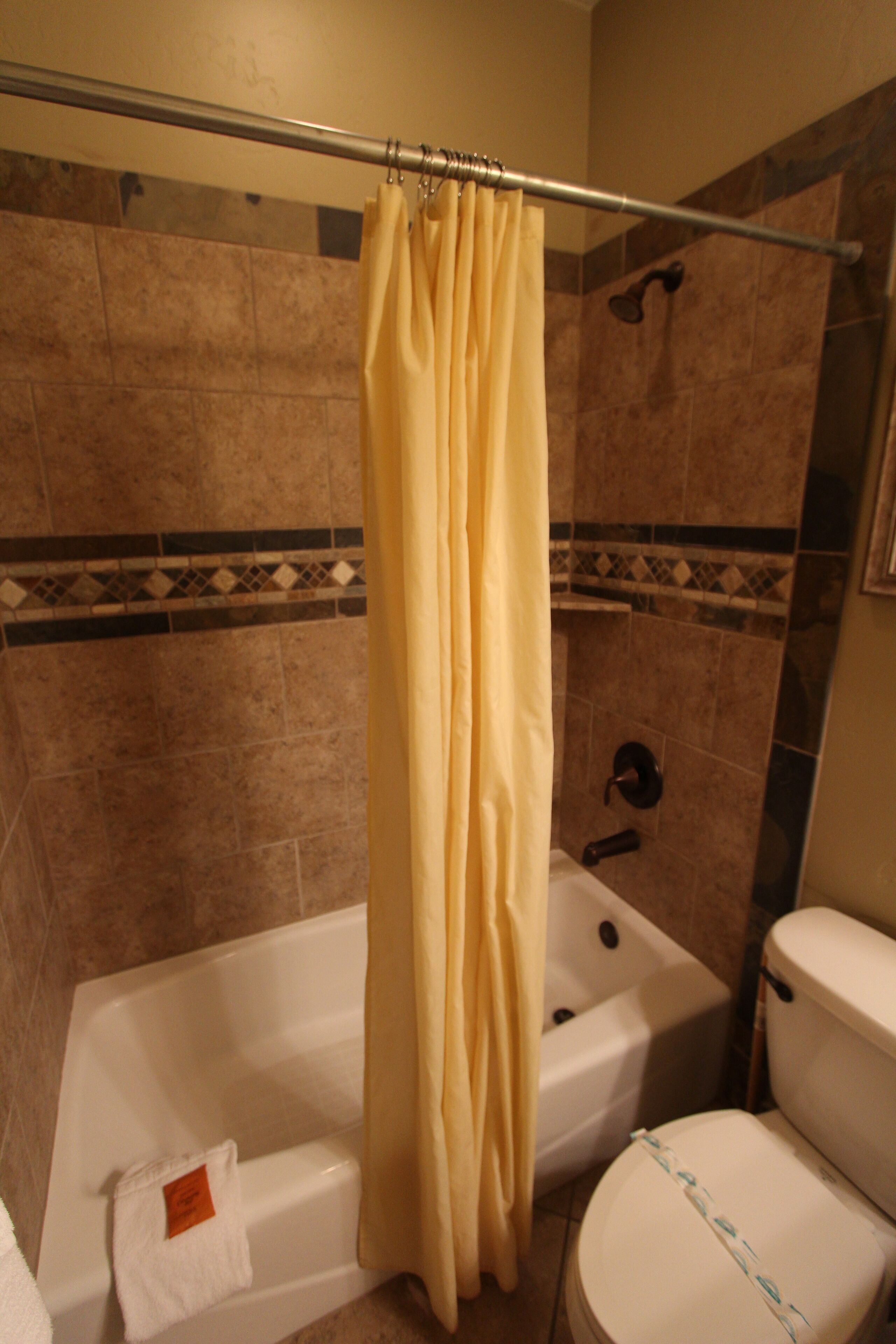 Une salle de bain avec une baignoire, des toilettes et un rideau de douche.