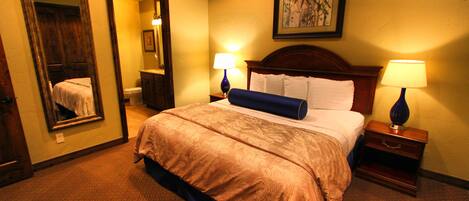 A hotel room with a large bed, two bedside tables with lamps, a mirror, and a framed picture on the wall.