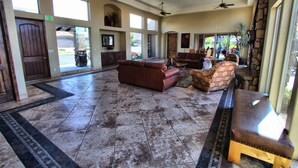 A spacious lobby with a high ceiling, large windows, and a variety of seating options including sofas and a bench. - Canyon Villas at Coral Ridge (Washington)