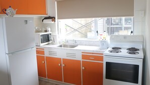 Une cuisine équipée d’un réfrigérateur, d’un four à micro-ondes, d’une cuisinière et de meubles de couleur orange.