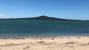 Une plage offrant une vue dégagée sur l’océan et sur une colline située au loin.