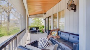 A covered porch with a black leather sofa, a small table, and a decorative pillow. - Private pool vacation home, spa, game rooms, HOA boat slip. (Lake Ozark)