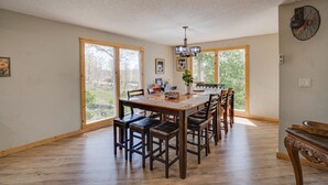 A spacious dining area with a wooden table and chairs, large windows, and a ceiling fan. - Private pool vacation home, spa, game rooms, HOA boat slip. (Lake Ozark)