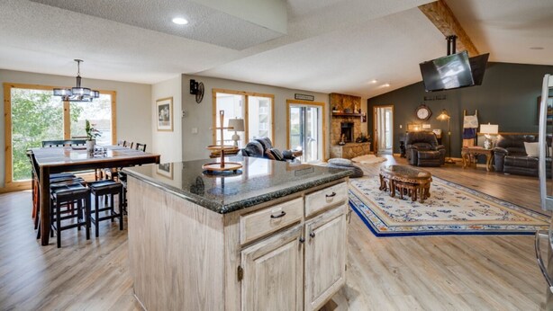 A spacious living area with a large wooden dining table, a fireplace, and a television mounted on the wall. - Private pool vacation home, spa, game rooms, HOA boat slip. (Lake Ozark)