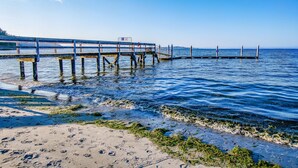 Une jetée s’avançant dans des eaux calmes, sous un ciel dégagé.
