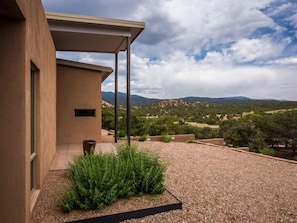 A modern building with a covered patio area, a gravel driveway, and a view of a mountainous landscape.