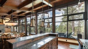 Une cuisine spacieuse dotée d’un grand îlot central, de meubles en bois et offrant une vue sur l’extérieur grâce à de grandes fenêtres.