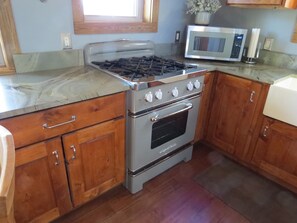 Kitchen features a stainless steel gas range, oven, and microwave, along with wooden cabinets and a countertop.